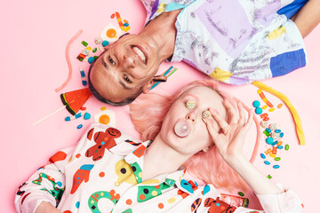 Young couple making bubble gum while lying with candies on floor