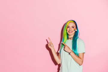 Young woman with rainbow makeup smiling while pointing fingers aside