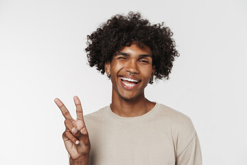 Young black man in t-shirt winking while showing peace gesture