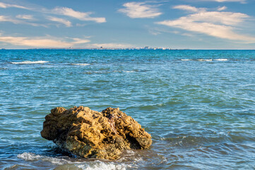 A rock in the foreground and in the BACKGROUND ON THE HORIZON the island of tabarca