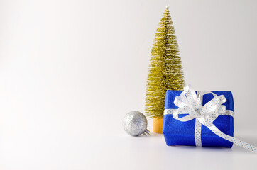 Christmas gift in blue glittering paper with white ribbon on a white background and eco-stick. Christmas present, new year, birthday, empty background