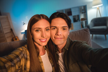 Photo of sweet charming young couple wear casual shirts smiling tacking selfie indoors house room