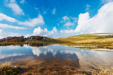 Small Lake or Pond used for cattle breeding with beautiful reflections. Lessinia high plateau, Regional Natural Park in Verona Province, Erbezzo, Veneto, Italy, Europe.