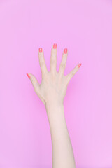 hand showing number five In front of the pink background