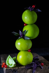 Tower of ripe green tomatoes on a dark background, rustic style