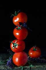 Tower of ripe red tomatoes on a dark background, rustic style