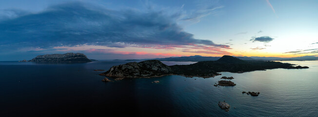 Fototapeta na wymiar View from above, aerial shot, panoramic view of a coastline with Tavolara Island in the distance during a dramatic sunset. Capo Ceraso, Sardinia, Italy.