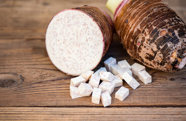 Fototapeta na wymiar Taro root with half and slice cubes on wooden background, Fresh raw organic taro root ready to cook