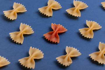 Pattern made of uncooked farfalle pasta on dark navy background. Macaroni background. Top view, flat lay. 