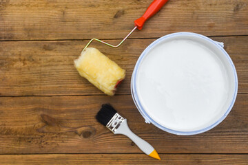 Painted tool with paint brush paint roller bucket canned paint for painting on wooden background, top view