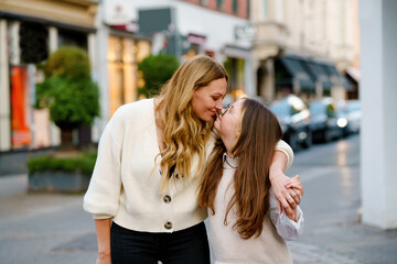 Fototapeta premium Young mother and school preteen girl making walk in the city. Happy family, woman and daughter with glasses enjoy time together. Love and support of parents. Happiness of mum and child.