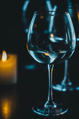 burning candles and glass goblets on a black background. bright candles and graceful glasses of wine on the dining table. glasses with white wine and candles