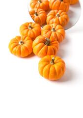 Orange decorative pumpkins with reflection in round mirror. Autumn and Halloween stylish home decor.