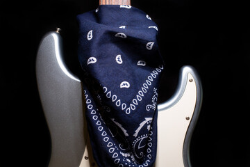 Silver electric guitar with blue bandana isolated on black background.