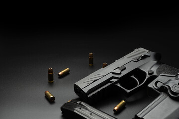 The black pistol is placed on a dark background, with 9 mm ammunition placed around it. And a...
