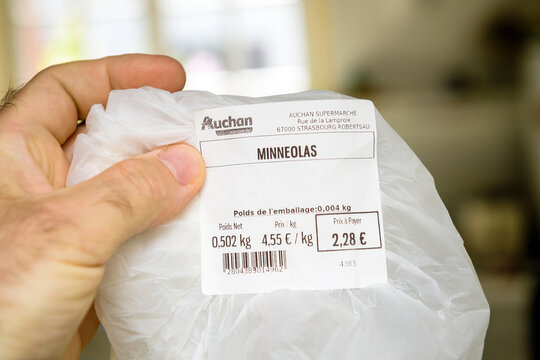 Paris, France - Apr 24, 2021: POV male hand holding plastic package with Minneolas - Nicknamed The Honeybell because of its bell shape