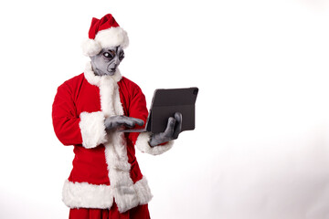 Santa Claus with alien mask wearing a tablet on a white background