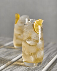 Homemade lemonade with ice in glasses on a wooden table and a slice of lemon