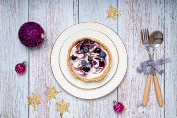 Christmas dinner table decorations with blueberry cheesecake on white porcelain plates.