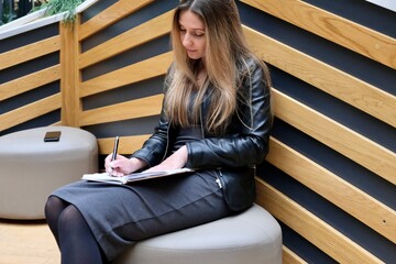 A brunette woman writes in a notebook (diary). The concept of training, training, freelance, remote...