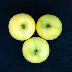 Ripe juicy yellow-green apples on a wood background