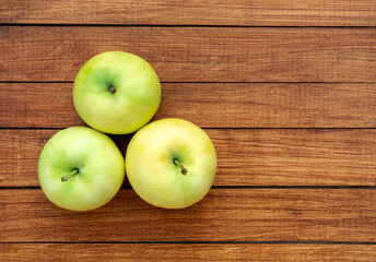 Ripe juicy yellow-green apples on a wood background
