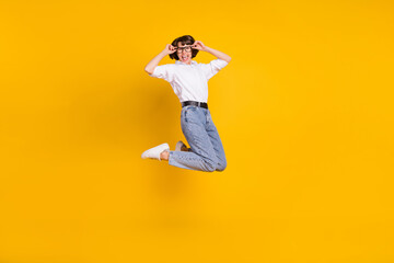 Fototapeta na wymiar Photo of cheerful business lady jump wear eyeglasses white shirt jeans sneakers isolated yellow color background