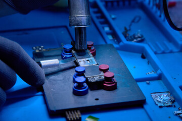 Hands in gloves of cellphone technology device maintenance engineer work on removing microprocessor...