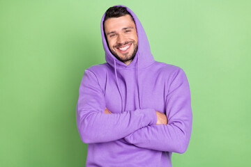 Fototapeta premium Photo of funky young brunet guy crossed hands wear violet hoodie isolated on green color background