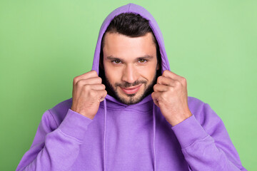 Photo of young handsome man happy positive smile wear hood pullover isolated over green color...