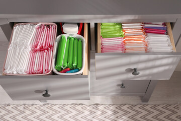Open cabinet drawers with menstrual pads, tampons and pantyliners indoors, above view - obrazy, fototapety, plakaty