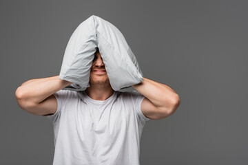 Angry man holding pillow near head isolated on grey