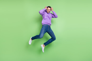 Full body photo of funny millennial brunet guy jump wear hoodie jeans sneakers isolated on green background