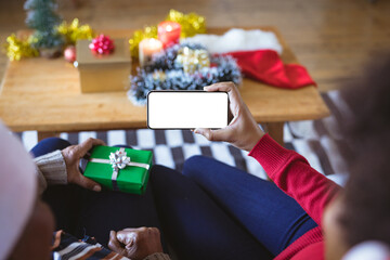 African american adult daughter and mother on christmas smartphone video call, copyspace on screen