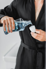 Cropped view of man pouring mouthwash in cap in bathroom - obrazy, fototapety, plakaty