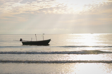 The fishing boat floats in the middle of the sea in the evening.