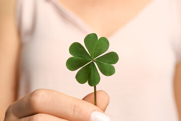 Woman holding green four leaf clover in hand, closeup