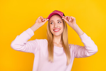 Obraz na płótnie Canvas Photo of young cheerful girl happy positive smile hands touch hat look empty space isolated over yellow color background