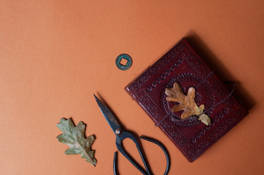 Occult book of spels and vintage scissors on orange fall color minimalistic background