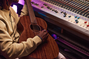 Close-up of African musician playing guitar during his work in the music studio