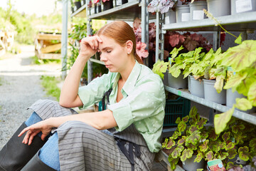 Woman as a gardener sits exhausted in the nursery