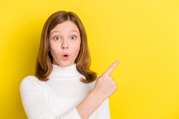 Photo of young girl amazed shocked surprised point finger empty space advert isolated over yellow color background