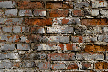 Dark red brick old wall with gray cracked paint, horizontal destroyed brickwork exterior outdoors, close-up. Textured grunge stone background