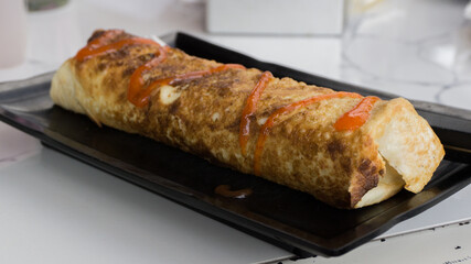 Burrito wraps with egg omelet and vegetables on plate. Turkish kebab with egg omelet and vegetables