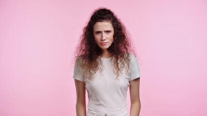 dissatisfied young woman looking at camera isolated on pink