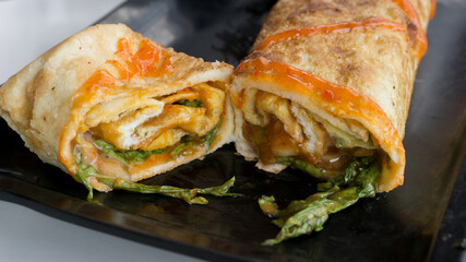 Burrito wraps with egg omelet and vegetables on plate. Turkish kebab with egg omelet and vegetables
