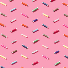 Colorful sewing threads on pastel pink background. Creative minimal concept.