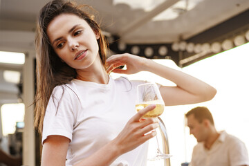 Young woman holding a wineglass and sitting on deck of sailing yacht