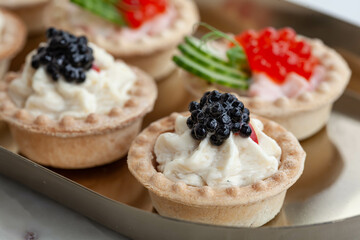 Black and red caviar tartlets on gold plate