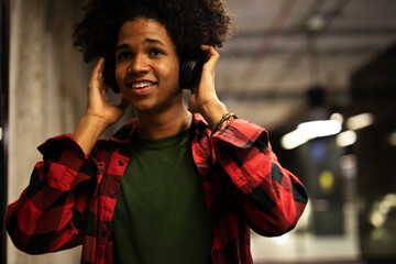 Cheerful guy listening music with the headphones. Young African man enjoying in music.